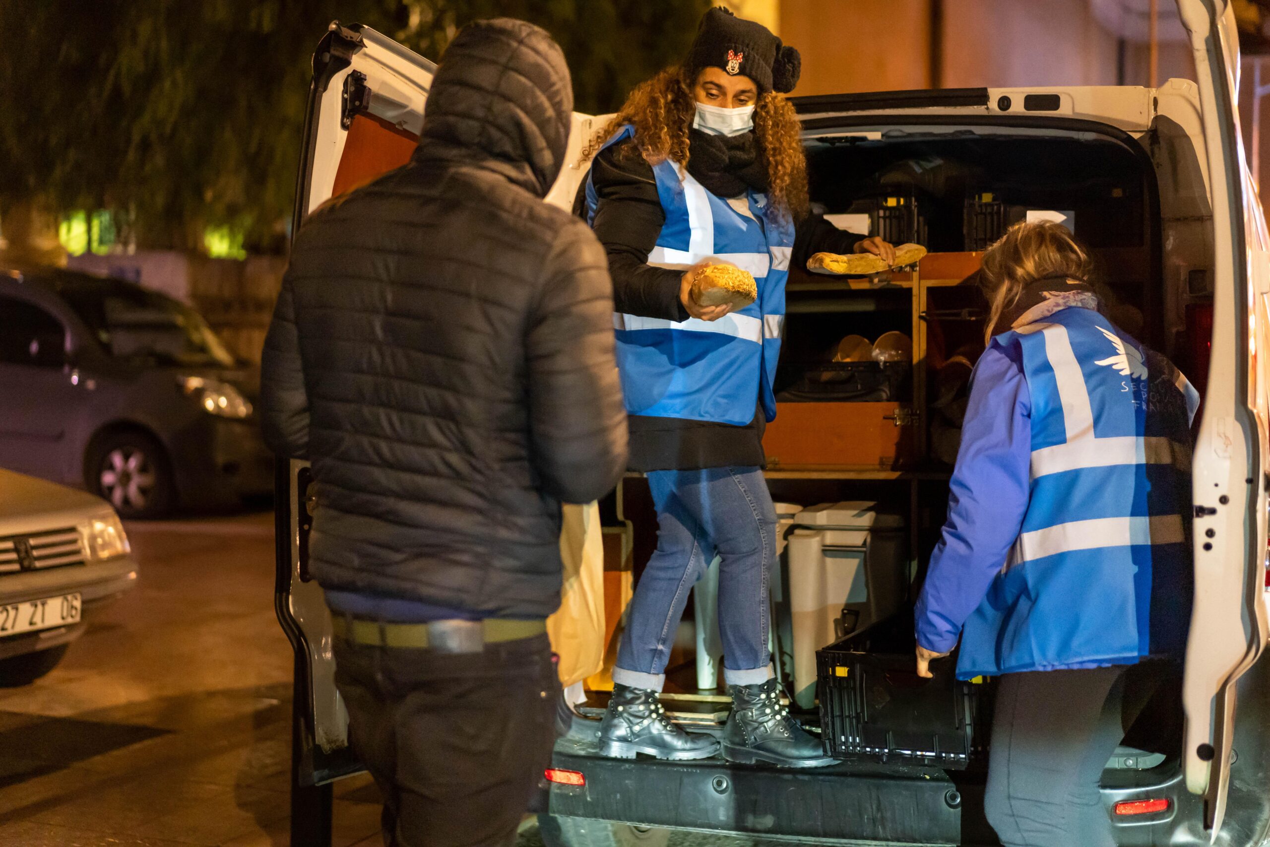 La camionnette du Secours populaire s'est arrêtée près de l'église du Voeu. Ismaan apporte des morceaux de pain qui accompagnent les colis alimentaires.