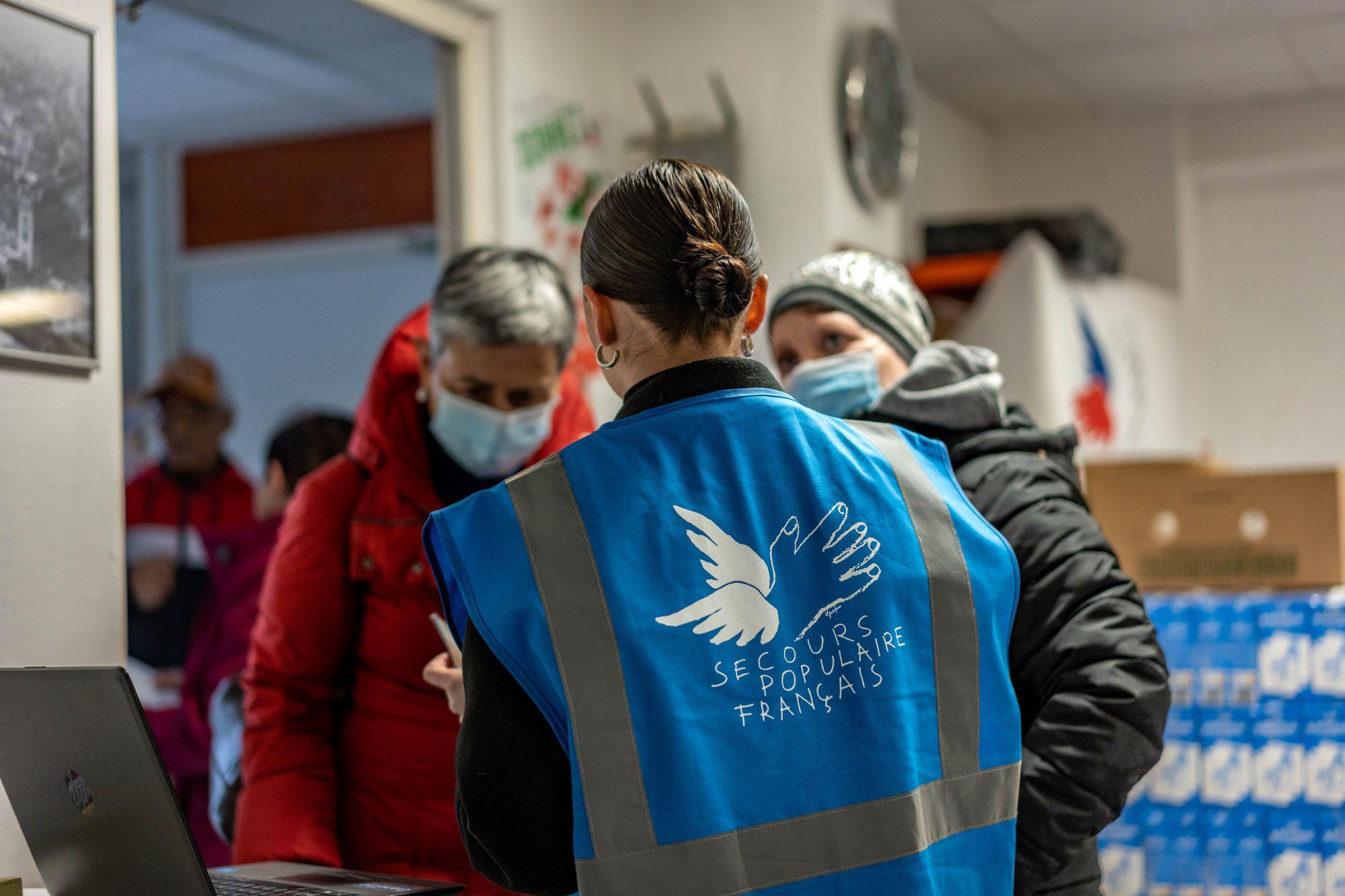 La jeune bénévole Anaïs explique aux personnes aidées que le Secours populaire est lui aussi frappé par la hausse des prix et les encourage à participer au Don’actions pour lui donner les moyens d'agir.