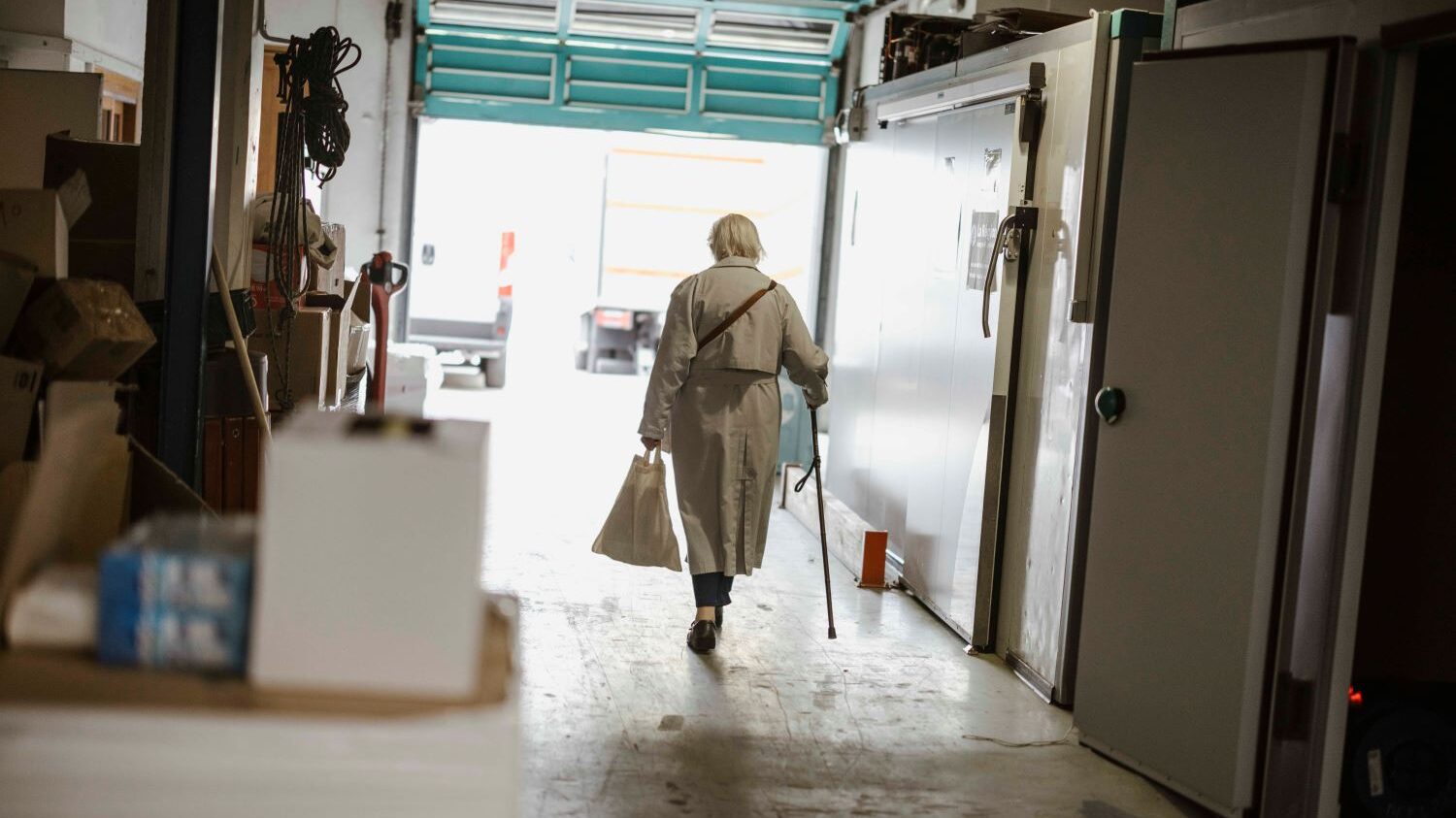 Une femme âgée s'éloigne en sortant d'un vestiaire du Secours populaire.