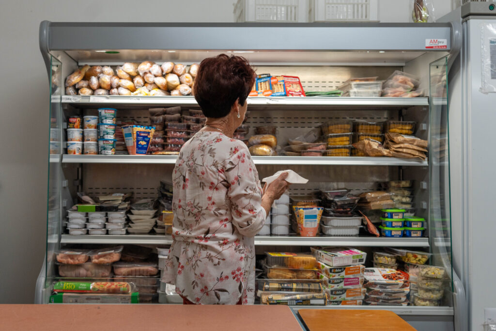 Femme faisant son choix de produits alimentaires devant un rayon de produits frais.