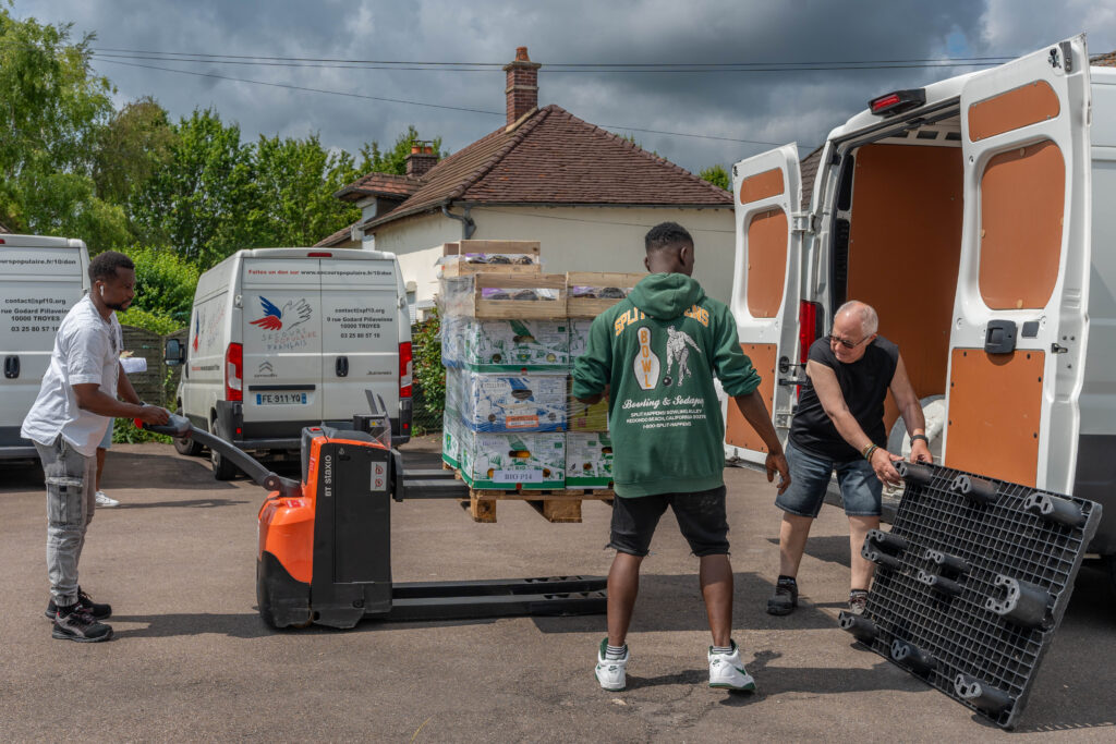 Trois bénévoles sortant les denrées du camion du SPF à l'aide d'un chariot élévateur.