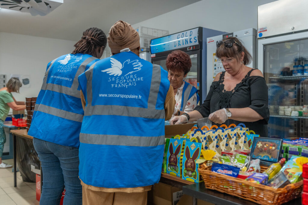 La secrétaire générale de la Fédération de l'Aude ainsi que trois bénévoles constituent un carton de denrées alimentaires.