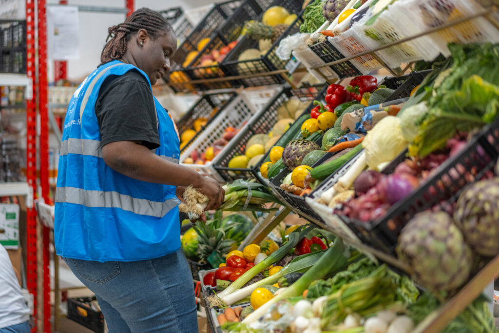 Bénévole choisissant sur l'étal des poireaux à distribuer.