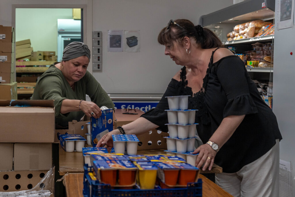 Femme accueillie qui choisit des yaourts proposés par la bénévole.
