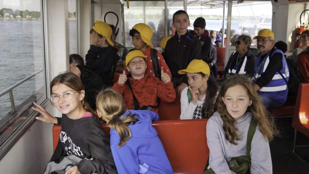 Plusieurs enfants à bord du bateau, l'un levant les pouces en l'air.