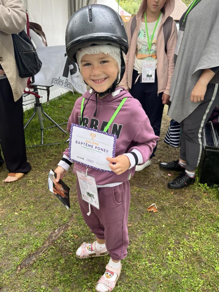 petite fille souriante avec son diplôme de baptême de poney