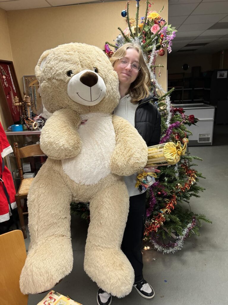 jeune fille avec un gros ours en peluche devant le sapin