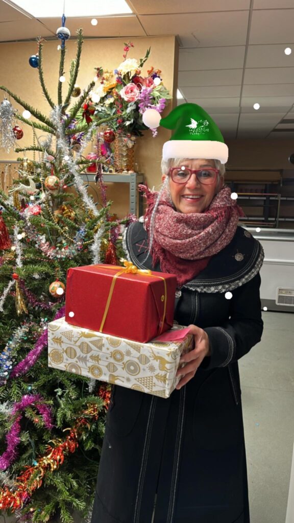 une bénévole qui remet des boites de Noël