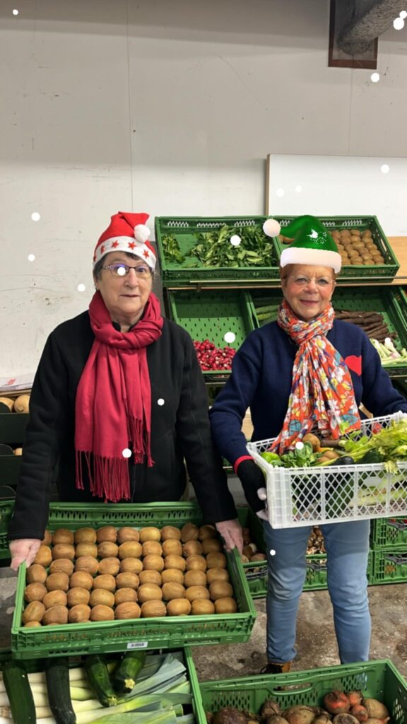 deux bénévoles qui préparent les colis de Noël, caisses de légumes et de fruits.