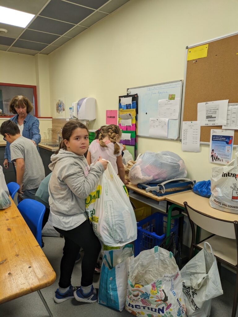 Une élève de l'école primaire de Nohic donne des denrées alimentaires au Secours populaire