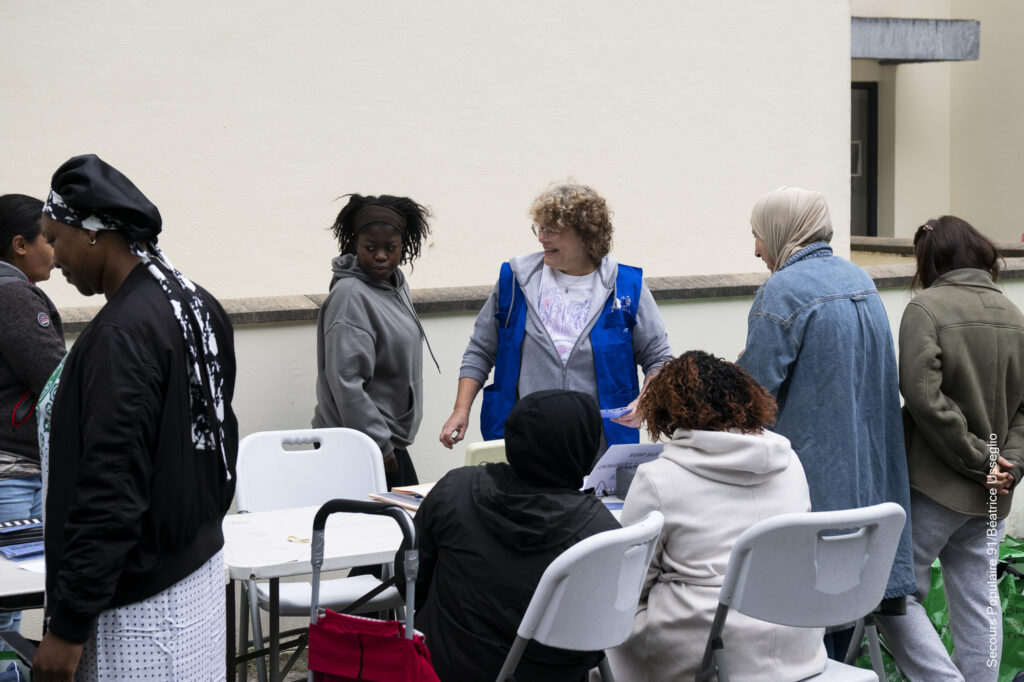 Groupe de personnes en train de discuter avec les bénévoles du Secours populaire.